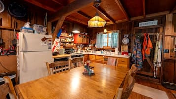 Una cocina rústica con vigas de madera, una mesa de comedor de madera y una lámpara colgante.