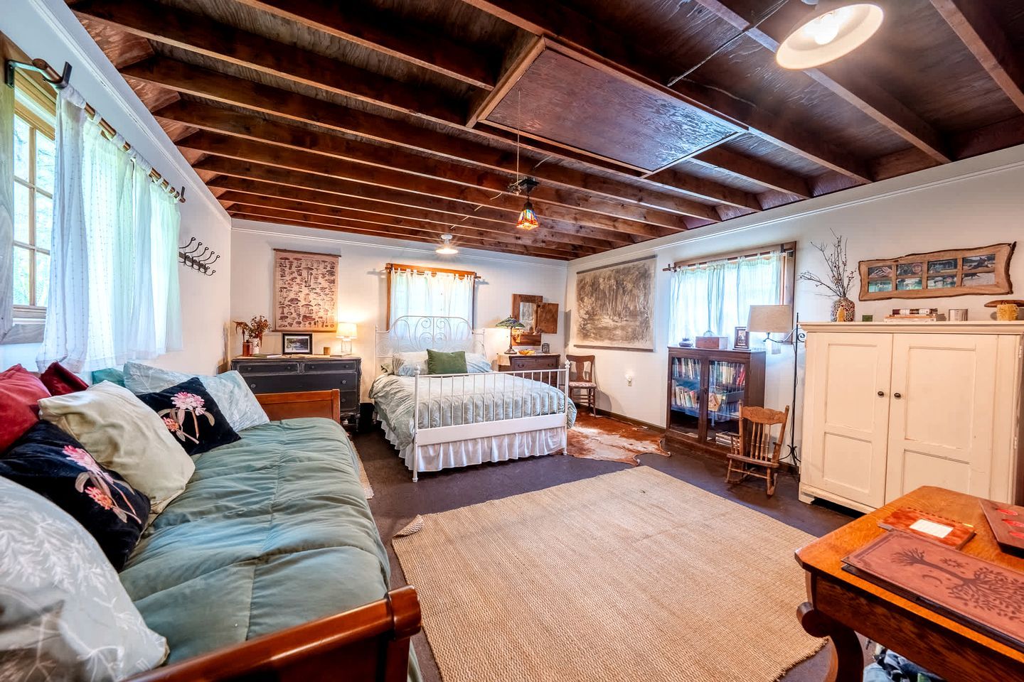 Una habitación acogedora con una cama, un sofá, un escritorio y un armario.