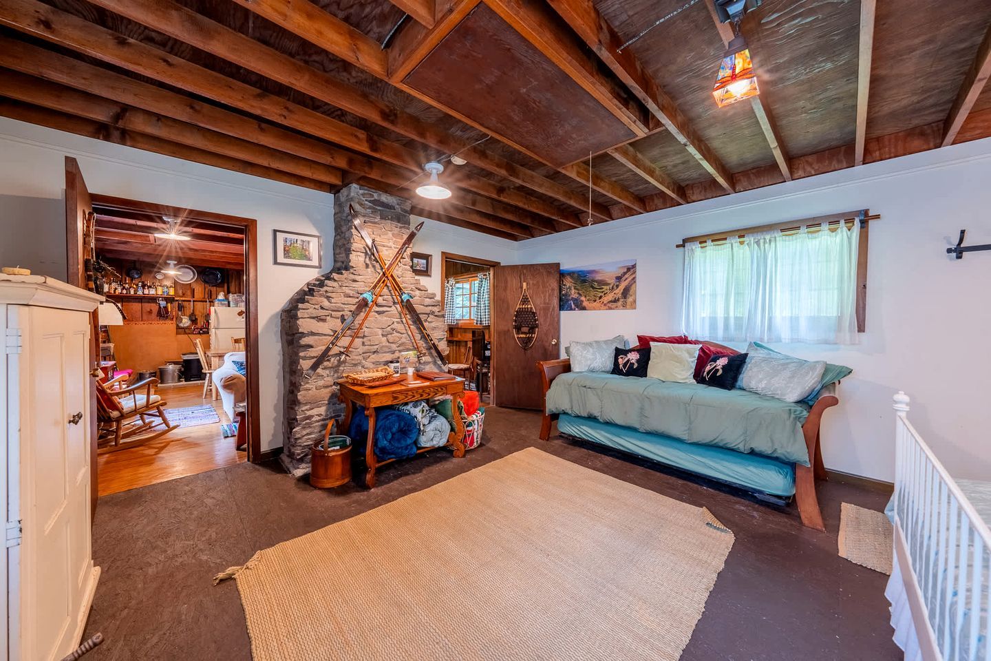 Un interior rústico con vigas de madera a la vista, una chimenea de piedra, un sofá acogedor y una zona de comedor con mobiliario de madera.