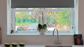 Una cocina con ventana, un fregadero y un florero con flores.