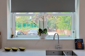 A kitchen with a window, a sink, and a vase with flowers.