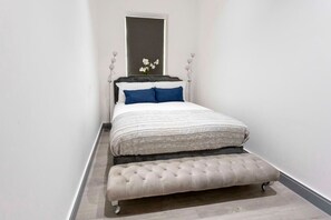 A bedroom with a bed, a bench, and a mirror.