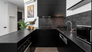 Una cucina moderna con mobili neri, un lavello in acciaio inossidabile e un forno integrato.
