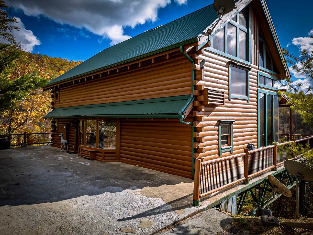 A log cabin with a green roof, a porch, and a satellite dish.
