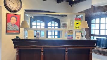 A reception desk with a clock, framed portrait, and warning signs.