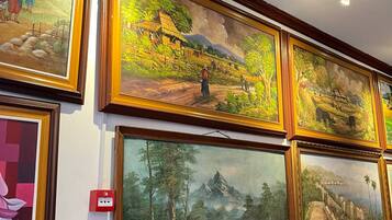 A wall with multiple framed paintings of landscapes and figures.