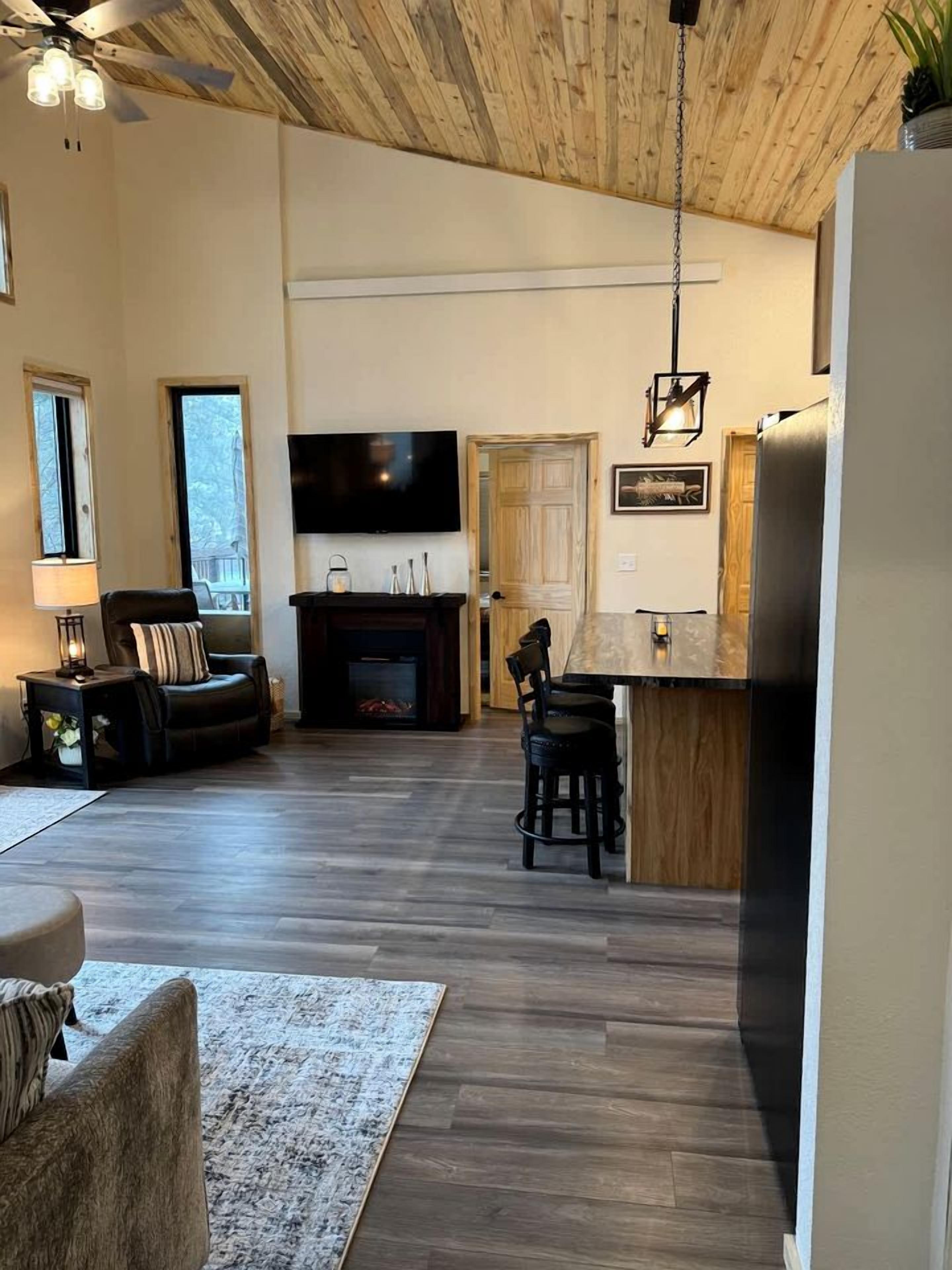 A living room with a fireplace, a television, and a dining area with chairs.