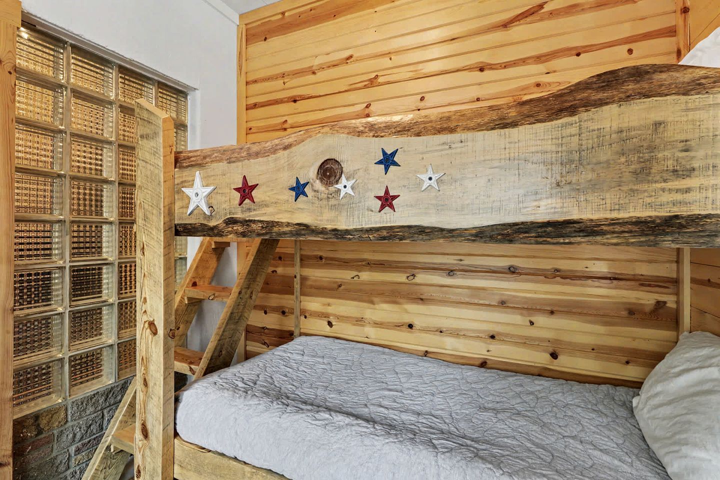 Una cama litera con cabecera de madera, una escalera y una pared con diseño de cuadrícula.