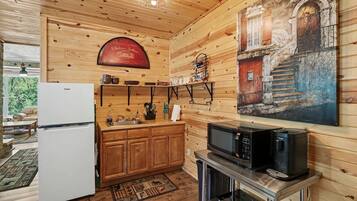 A wooden interior with a kitchen area, including a refrigerator, microwave, and stove.