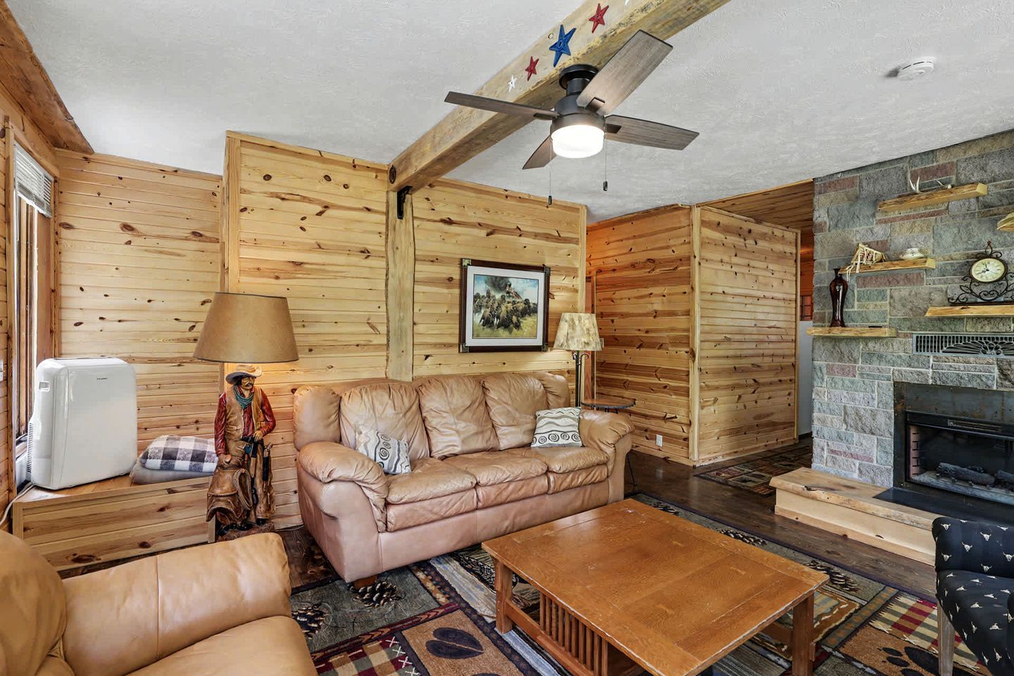 Interior acogedor de una cabaña con techo de madera, chimenea, sofá de cuero y una mesa de comedor.