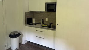 A modern kitchen with a microwave, sink, and a trash bin.