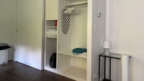 A room with a wardrobe, a radiator, and a trash bin.