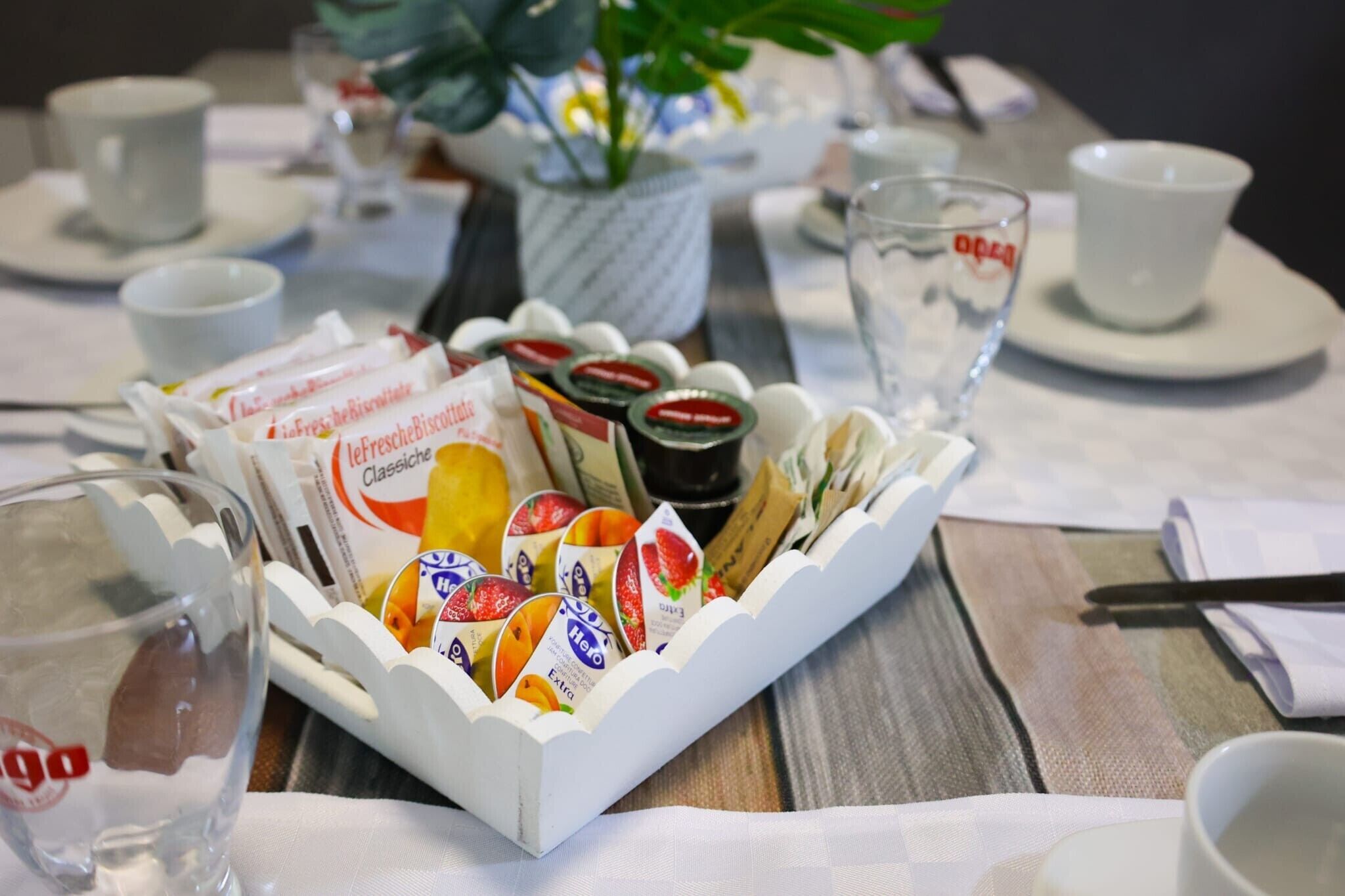 A dining table with a tray of assorted food items, a potted plant, and a glass of water.