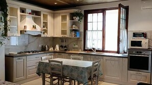 Una cocina compacta con comedor, armarios empotrados, microondas y ventana con cortinas.