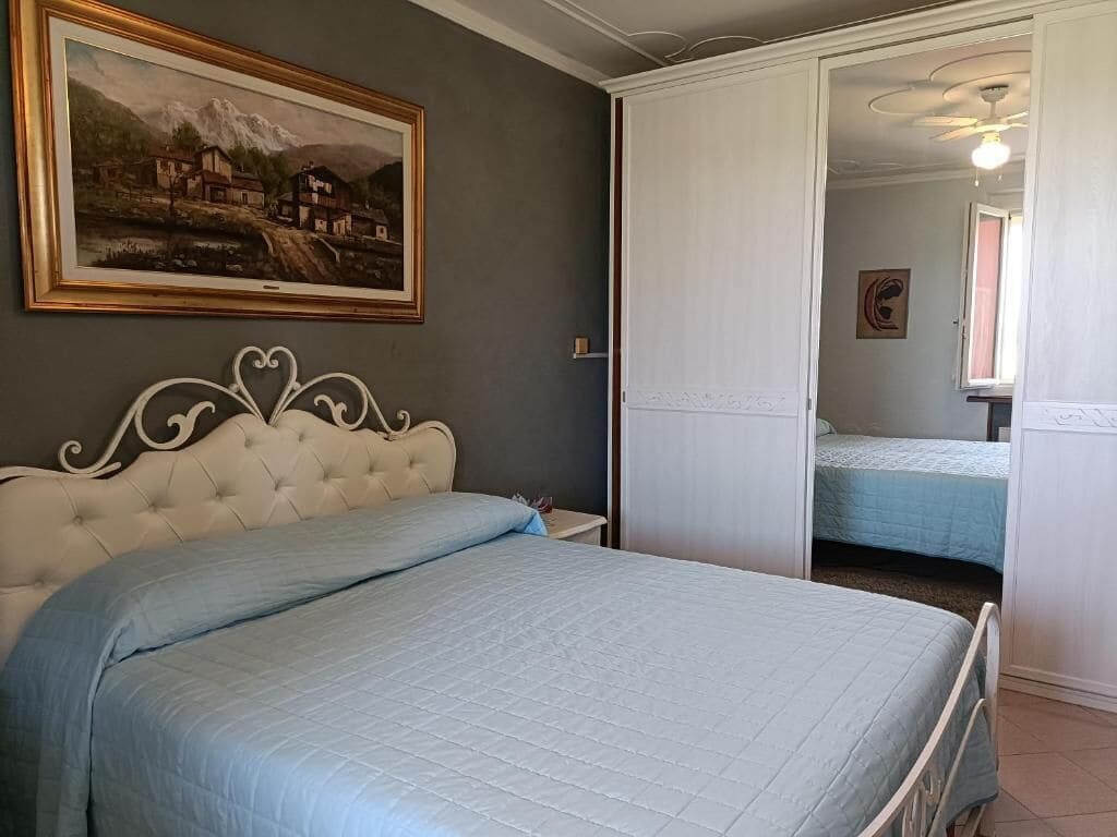 Un dormitorio con cama, armario, un cuadro y ventana.