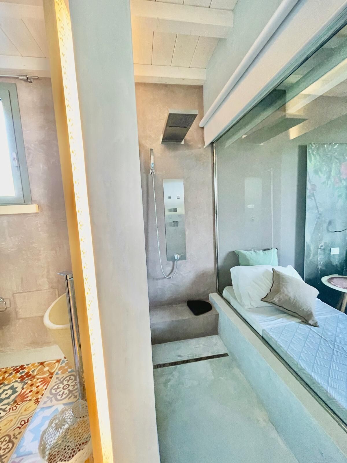 A modern bathroom with a shower, a toilet, and a bed with pillows.