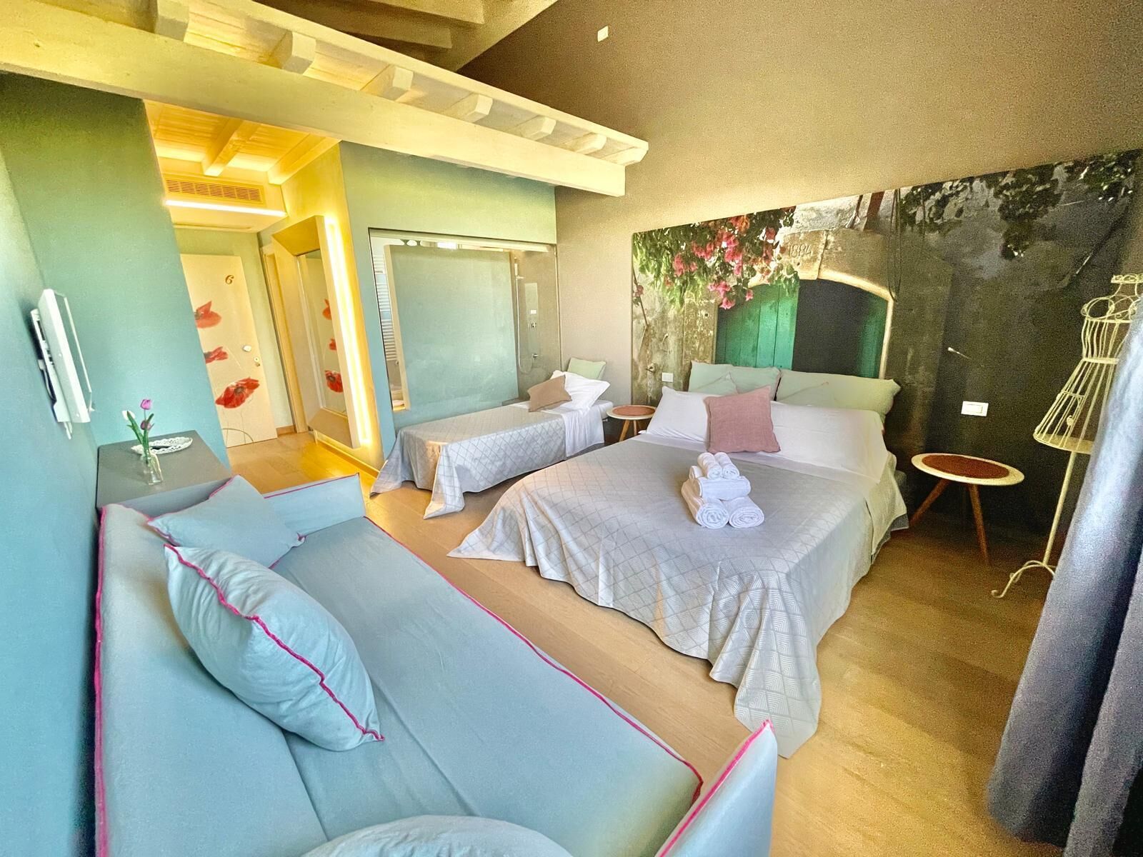 Une chambre d’hôtel avec deux lits, un canapé, une petite table et un mur décoratif.