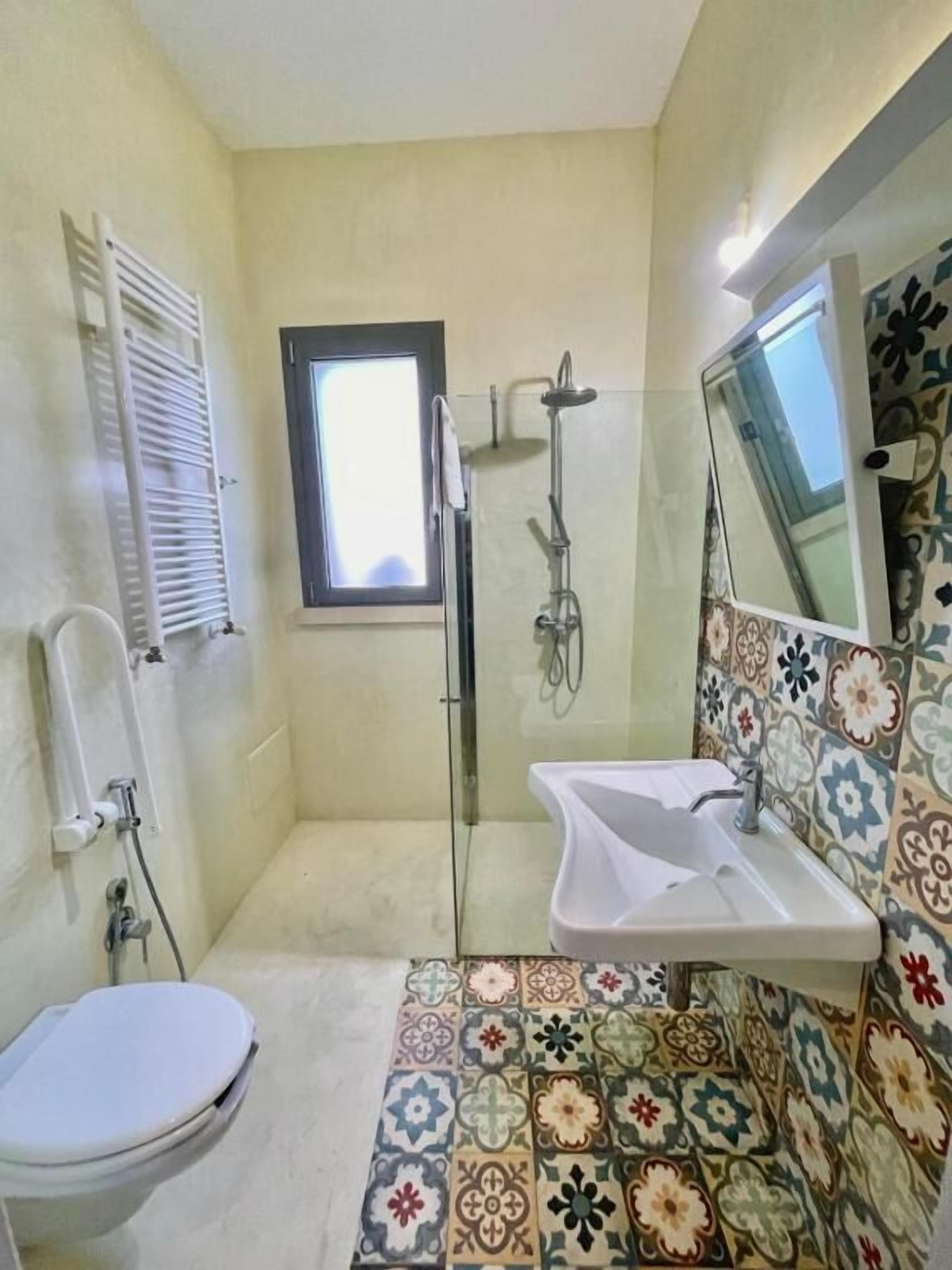 Une salle de bain équipée de toilettes, d’une douche, d’un lavabo et d’une fenêtre.