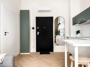 A modern kitchen with white cabinetry, a black door, and a herringbone wood floor. - Premium Apartment with A/C, city center Cracow, Dąbrowskiego (Kraków)