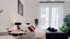 Een hotelkamer met een bed, nachtkastje en een raam met gordijnen.