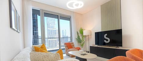 A modern living room with a sofa, ottoman, coffee table, and a flat-screen TV.