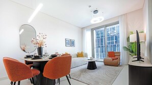 Een moderne woonkamer met een eethoek, grote ramen en een flatscreen televisie.