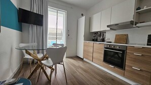 Una cuina moderna amb armaris de fusta, forn de dipòsit i menjador amb taula i cadires de vidre.