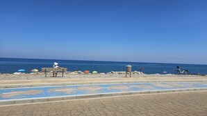 Una platja amb passeig, bancs, ombrel·les i una bicicleta.