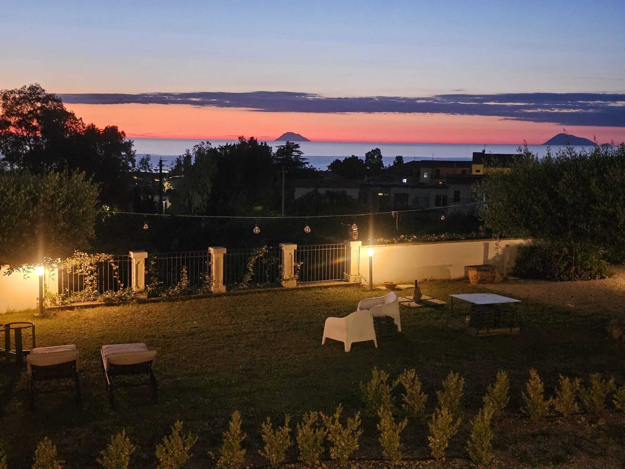 A backyard with a view of the sunset, a fence, and outdoor furniture.