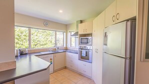 A modern kitchen with a dishwasher, microwave, oven, and refrigerator. - Farrant Family Escape – Roomy Wanaka Retreat (Wānaka)