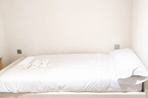 A single bed with white bedding and towels, a bedside table, and a wall socket. - 1A173 Cozy Apartment in Gijón (Gijón)