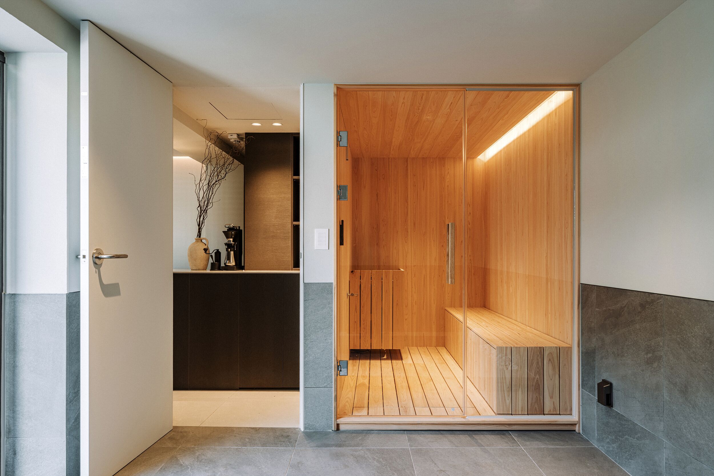 A modern bathroom with a wooden shower enclosure, a sink area with a vase, and a tiled floor.