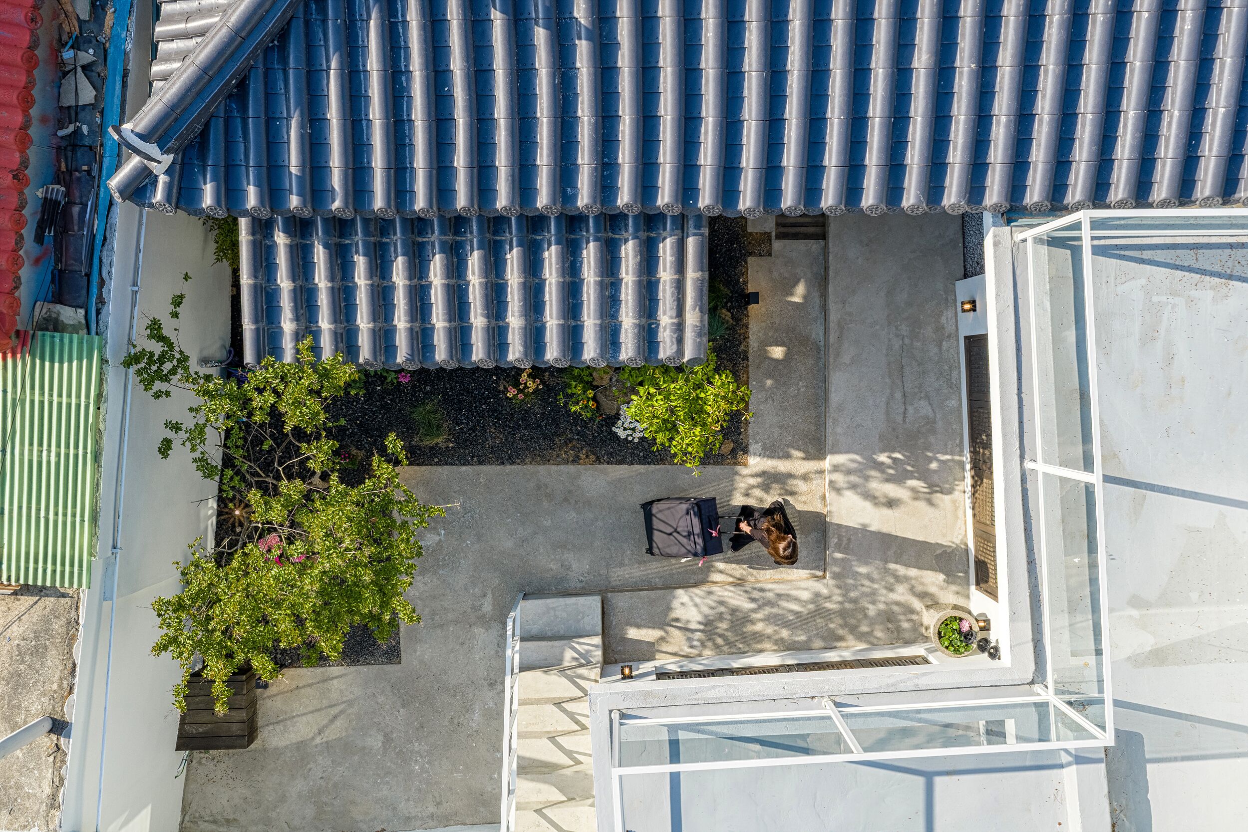 A residential building with a tiled roof, a small garden area with potted plants, and a bicycle parked outside.