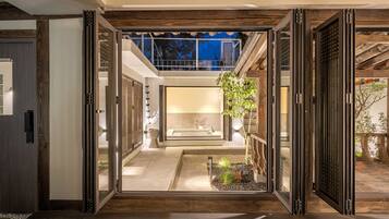 An open interior space with a view of a garden, a bathtub, and a staircase leading to a second floor.