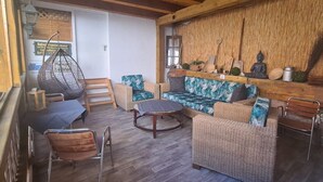 A cozy interior with wicker furniture, a hanging chair, and a wooden ceiling.