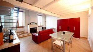 Eine moderne Küche mit Essbereich, roten Schränken und einem roten Sofa.