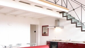 Eine moderne Küche mit einem roten Schrank, einem Glastisch und einer Treppe.