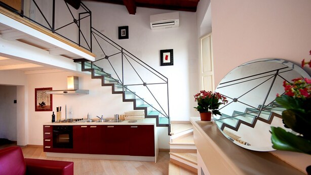 Eine moderne Küche mit Kochinsel, einer Treppe mit Glastrennwand und einem Essbereich mit einem roten Sofa.
