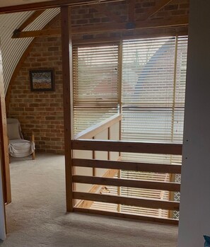 A room with a wooden gate leading to a balcony with a view of a brick building.