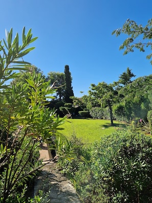 A lush garden with a variety of trees and shrubs, a clear blue sky, and a stone pathway. - Beachfront family villa with a pool, Domaine de Port d'Alon, sleeps 6–10 (Saint-Cyr-sur-Mer)