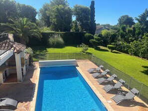 A swimming pool with a tiled deck, surrounded by a fence, and a grassy area with trees and shrubs. - Beachfront family villa with a pool, Domaine de Port d'Alon, sleeps 6–10 (Saint-Cyr-sur-Mer)