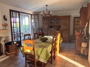 A dining area with a table set for four, surrounded by wooden chairs, a chandelier, and a cabinet with glass doors. - Beachfront family villa with a pool, Domaine de Port d'Alon, sleeps 6–10 (Saint-Cyr-sur-Mer)