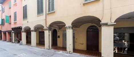 A row of buildings with arched doorways and a street in front.