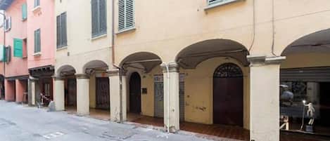 A row of buildings with arched doorways and a street in front.