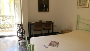 A room with a bed, two chairs, a desk, and a painting on the wall. - Spiritosa - casa della zia (Bologna)