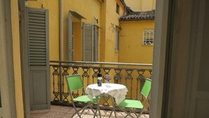 A balcony with a table and chairs, a window with shutters, and a door. - Spiritosa - casa della zia (Bologna)