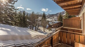 Un balcone in legno con vista su montagne innevate e alberi.