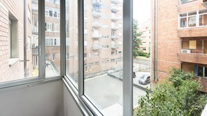 A view from a window of a multi-story building with balconies, a parking area, and adjacent buildings. - Mascarella (Bologna)