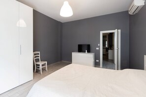 Une chambre à coucher comprenant un lit, une chaise, un téléviseur, une commode et une armoire.