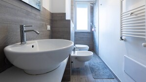 A modern bathroom with a large sink, toilet, and a shower area. - Mascarella (Bologna)